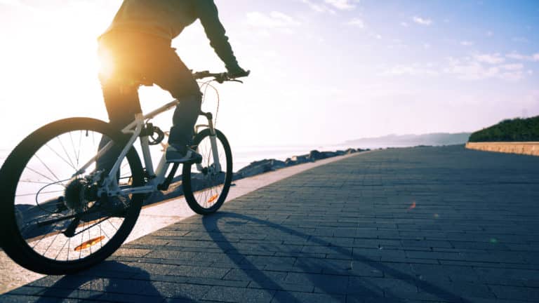 Person cycling bike with sunrise in background